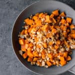 a bowl of granola-topped vegan maple roasted sweet potatoes