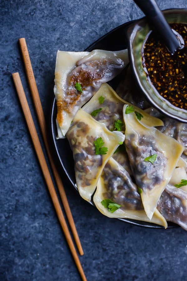 vegetable potstickers on a plate with chopsticks and dipping sauce